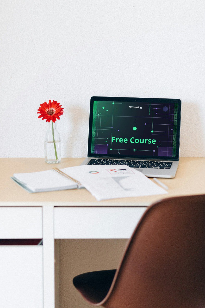 Laptop on a desk with a free course announcement on the screen, next to a notebook and a red flower.