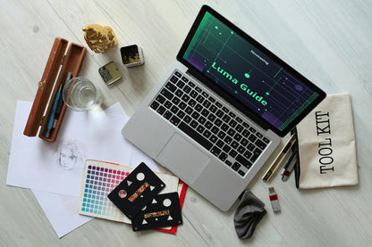 Laptop on a desk with various items including a glass of water, a pen case, and a tool kit bag.