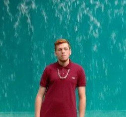 Person wearing a red shirt standing in front of a water fountain